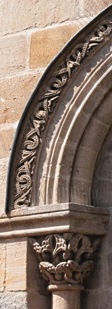 Left side of the tympanum. At the base of the arc, we can see interlaced foliage.